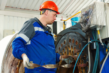Engineer in helmet inspects and repairs gas equipment of boiler room. Cleaning and maintenance of...