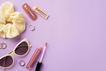 Make up concept. Top view photo of trendy sunglasses scrunchy pink lip gloss gold rings and two hairpins on isolated purple background with copyspace