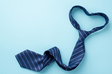 Father's Day concept. Top view photo of heart shaped blue necktie on isolated pastel blue...