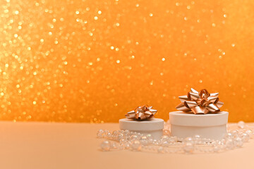 Round gift boxes with bows on top, on an abstract golden blurred bokeh background. Selective focusing and shallow depth of field. A holiday card.