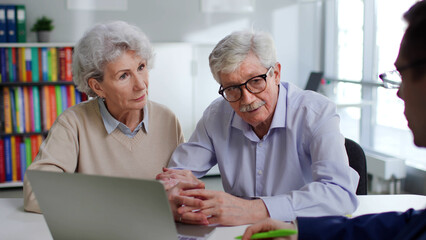 Insurance agent advising elderly couple about savings