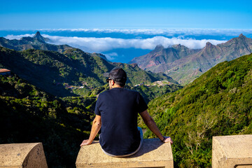 A tourist looking at the mountain range of Anaga in Tenerife with clouds. Tenerife