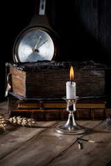 Burning candle on the background of old books on a wooden table