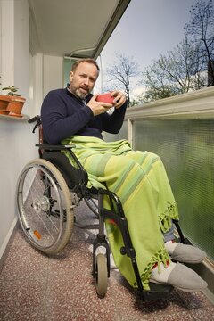Disabled man on wheel chair enjoying nice day on balcony