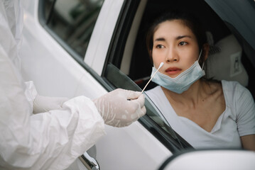 Doctor in a protective suit taking a nasal swab from a person to test for possible corona virus...