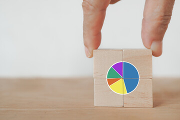 hand completed circle graph showing market share portion on wooden cube blocks with orange background