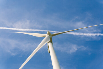 Sweden, Kristianstad – May 17, 2022: Huge wind turbines, electrical energy generators in a field outdoors, blue sky. 