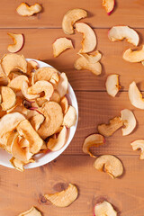 Ripe apple and dried apples in a bowl on wooden background . Harvesting and drying apples. Dried apple slices on the table. Dried fruit chips. Healthy vegan food.