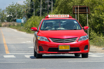 A red taxi car ride on a rural road