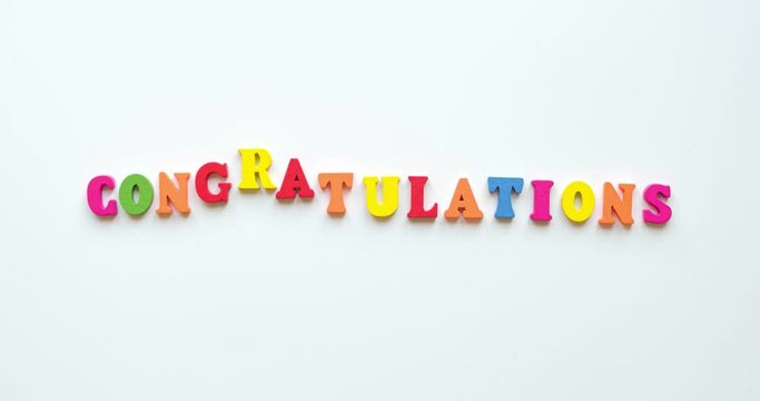 Text Congratulations from colorful wooden letters on white background. 4K looped stop motion animation