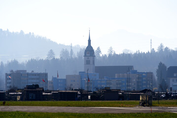 Catholic church St. Mauritius at City of Emmen with Swiss Air Force Airbase Emmen, Canton Lucerne, in the background on a sunny spring day. Photo taken March 23rd, 2022, Emmen, Switzerland.