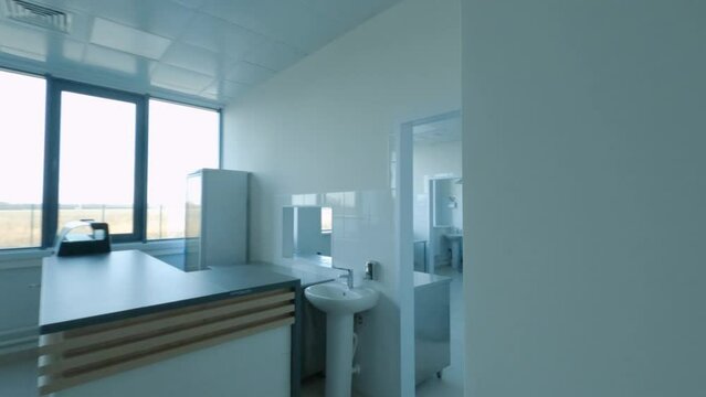 Motion along empty semi-dark corridor to spacious medical offices with equipment in contemporary hospital drone first point view