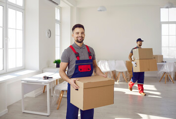 Smiling deliverymen with cardboard boxes load packages help client with moving or relocation....