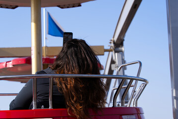 Rear view of woman up in the sky in red ferris wheel cabin looking over the City of Zürich on a beautiful spring day. Photo taken March 28th, 2022, Zurich, Switzerland.