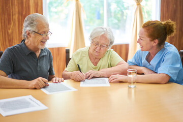 Altenpflegerin betreut Senioren beim Rätsel lösen