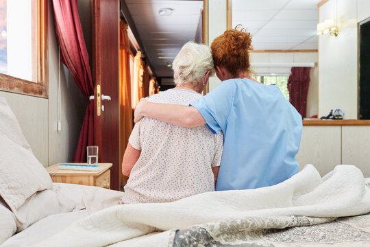 Krankenpflegerin umarmt Seniorin in Hospiz zum Trösten