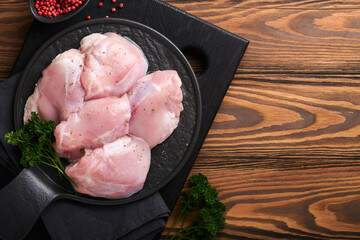 Raw chicken thigh fillet without skin with herbs and spices on old wooden background. Farm poultry meat. Top view with copy space. Mock up. - obrazy, fototapety, plakaty