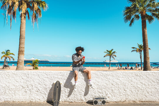 African Man Having Fun Doing Selfie With Mobile Phone With Beach On Background - Focus On Face