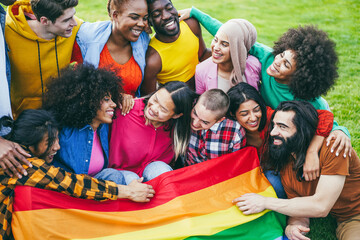 Diverse people having fun holding LGBT rainbow flag outdoor - Focus on bald girl face