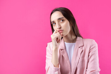 Portrait of beautiful young woman in pink jacket thinking isolated on red background