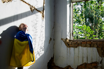 Destroyed Ukrainian houses. War in Ukraine. The child prays for peace. The child dreams of ending the war. Children against war. Peace concept. Children in a bomb shelter. child in ruins