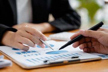 Company meeting room has businessmen and finance managers meeting together on finance topics, they are looking at information on documents and discussing together. Concept company financial management