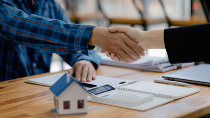 The salesperson of the housing estate in the project and the customer shake hands after...