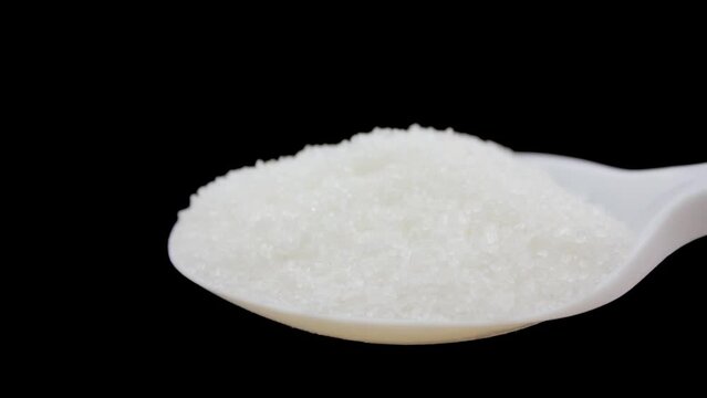 Sugar in a spoon on a black background close-up. White sugar close-up.