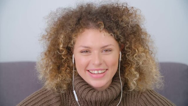 Happy young woman in headset talking on a video call. Portrait of a cheerful and friendly female person speaking in camera with a smile
