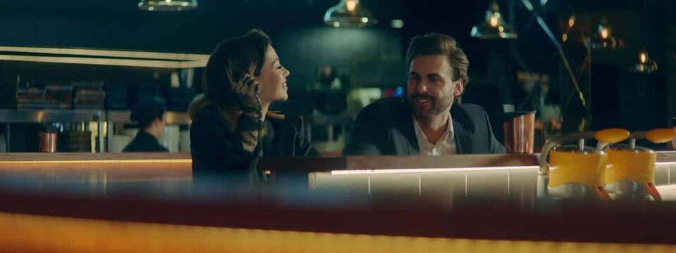 Beautiful Caucasian couple having a date in a stylish restaurant, talking and laughing. Shot with 2x anamorphic lens