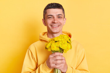 Indoor shot of smiling delighted Caucasian young adult man wearing casual style hoodie, holding...
