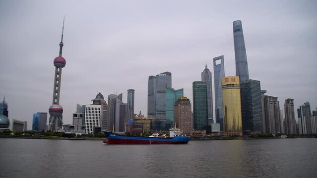 Time Lapse View on Shanghai Skyline over the Bund river with big boat driving over the river on cloudy day