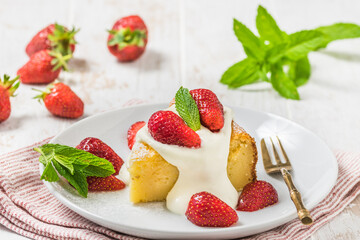 Piece of homemade cheesecake with whipped cream and fresh strawberries on white wooden background