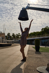 portrait of a young woman under a sculpture of a lamp in malaga on a hot sunny summer day