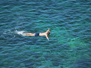 A free diver swimming in a blue, transparent sea.