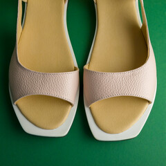 women's beige shoes lie on a green background. Shoes are located at an angle to the horizon. Square...