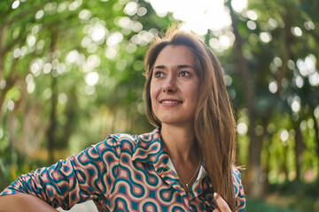 happy young white woman in a park with lots of greenery on a warm sunny summer day