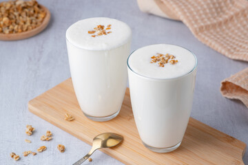 Kefir, buttermilk or yogurt with granola. Yogurt in glass on white wooden background. Probiotic...