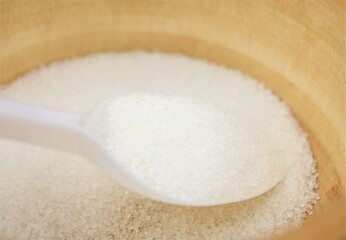 Sugar in a wooden bowl. Sugar and spoon.Sugar consumption concept.