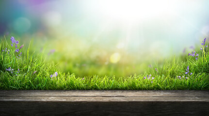 A wooden table product display with warm summer garden background of green grass and blurred foliage with strong sunlight.