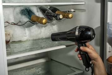 Thawing ice from a fridge with the help of a hair dryer.