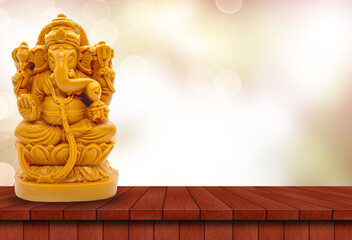 Hindu God Ganesha on a wooden table with blurred bokeh background