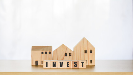 Real estate investment concept. Wooden block with text invest and model houses, real estate growth in the future, finance, banking, lending, and trading.