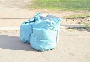 two polyethylene bags and a container with plastic waste on the street