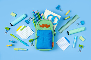 Opened Pencil case with stationery  on blue background. Concept back to school. School supplies.