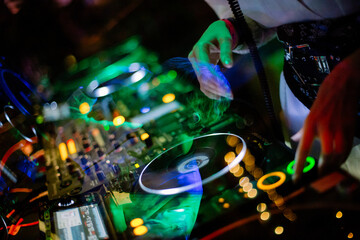 girl dj plays a set in a nightclub. girl dj at the dj console against the backdrop of a nightclub,...