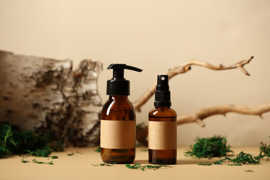 SPA natural organic cosmetics packaging design. Amber glass dispenser and spray bottle with blank labels mockups. Tree branch, birch bark and moss on background.