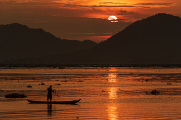 Fishing under a full round sun during a beautiful sunset