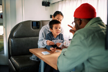 Parents teach their son card games in their van.