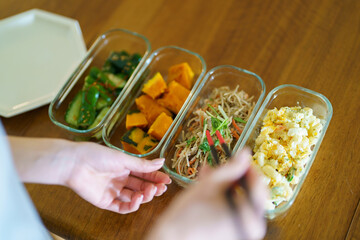 作り置きしたお惣菜をお皿に盛る女性